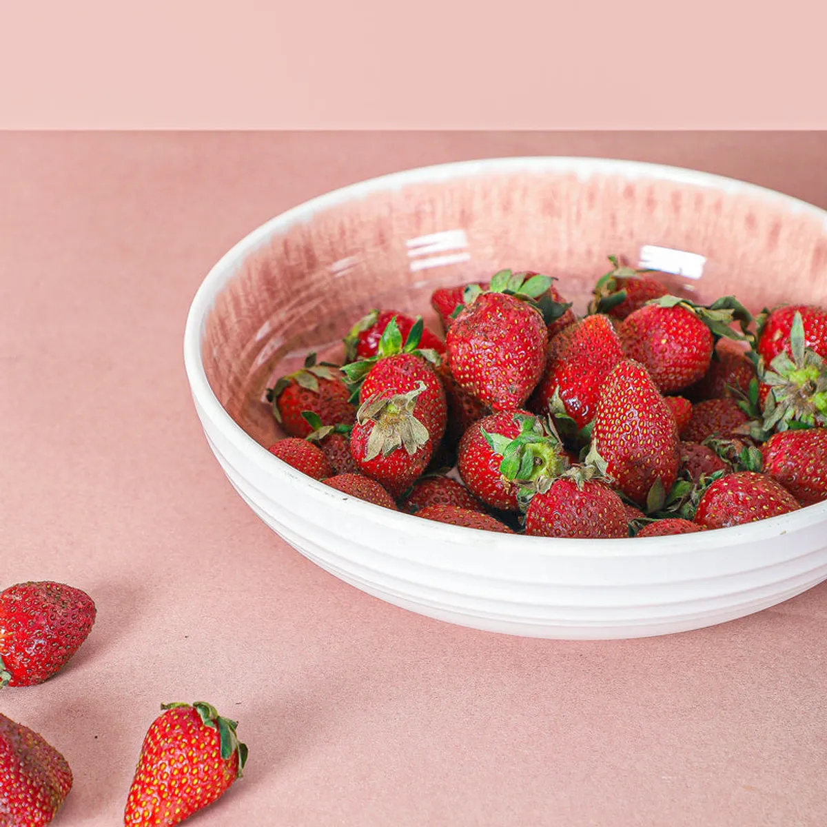 Close-up of a white and blush pink bowl filled with strawberries