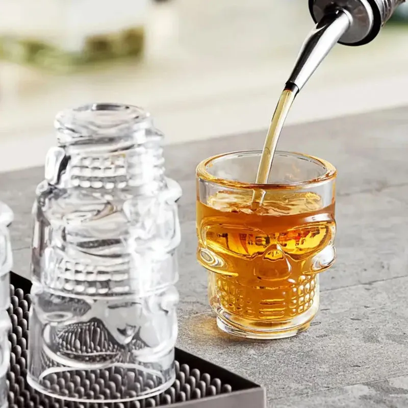 Clear skull shot glass being filled with a drink beside an inverted glass