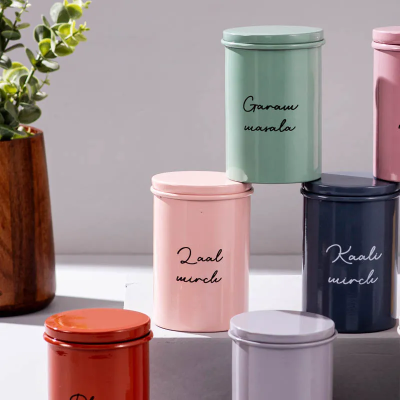 Close-up of pastel green, pink and navy cylindrical storage jars with script labels