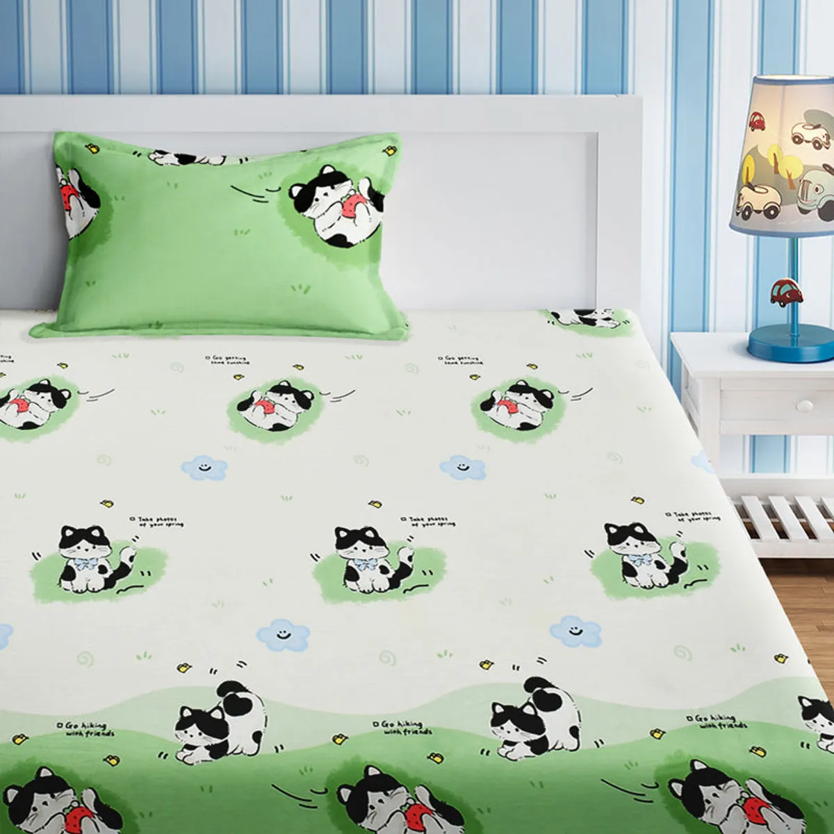 Children's bed dressed in a white and green cat-print flat sheet