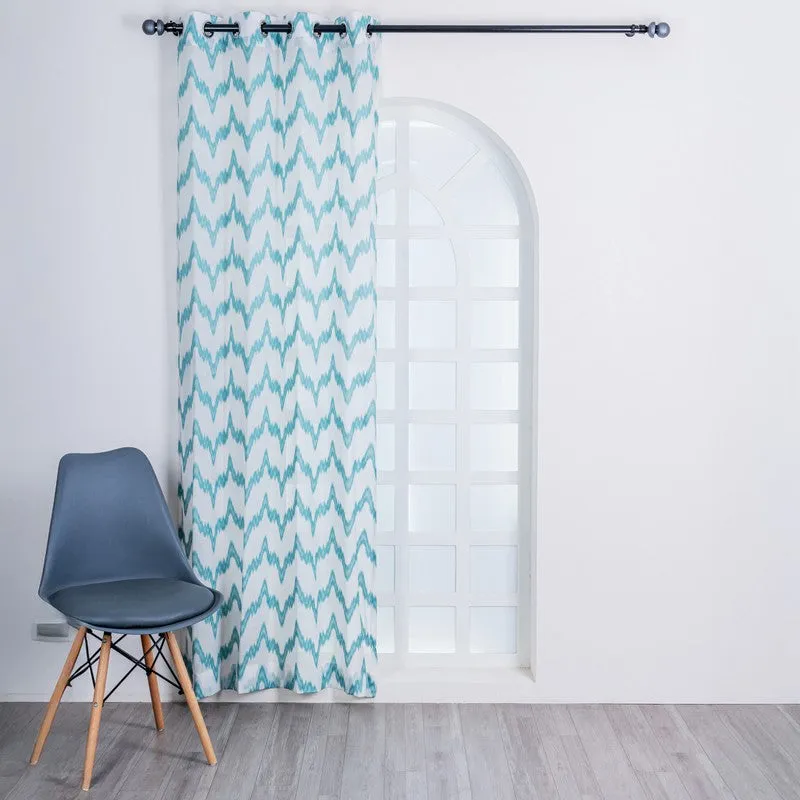 Single blue and white patterned curtain covering an arched window.
