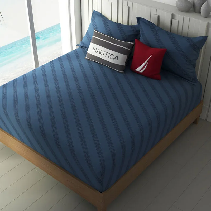 Navy blue diagonal striped bedsheet on a double bed beside a bright window