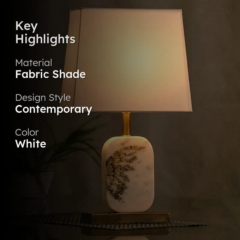 Lit white table lamp with marble base and rectangular fabric shade