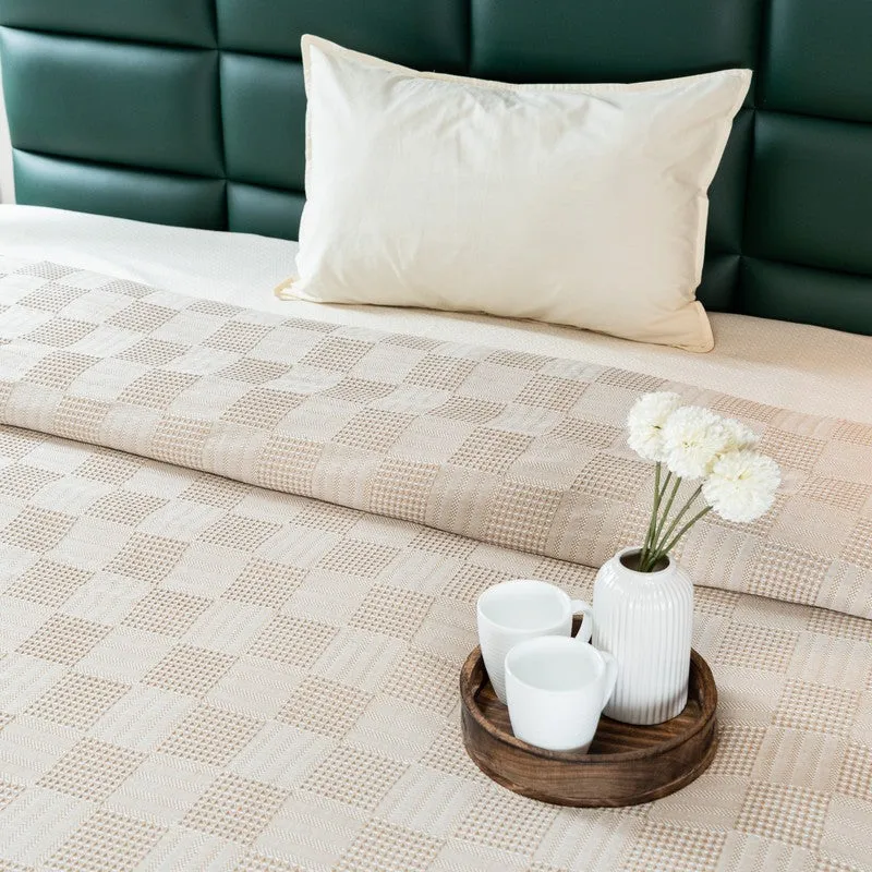 Folded beige bedsheet with textured geometric surface and pillow