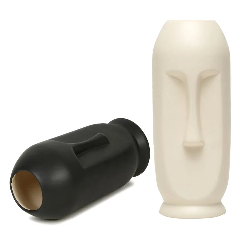Black face vase lying sideways beside a white face vase