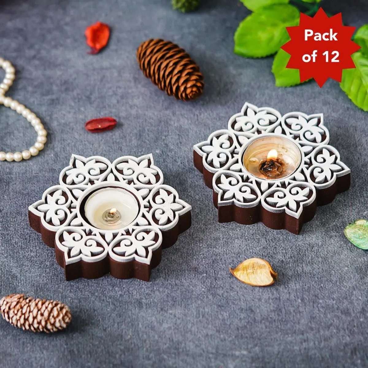 Two floral wooden tea light holders in brown and white on a grey surface
