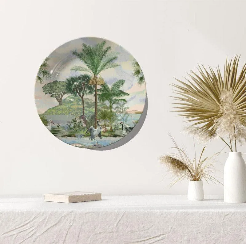 Round wall plate with tropical landscape artwork hung above a table