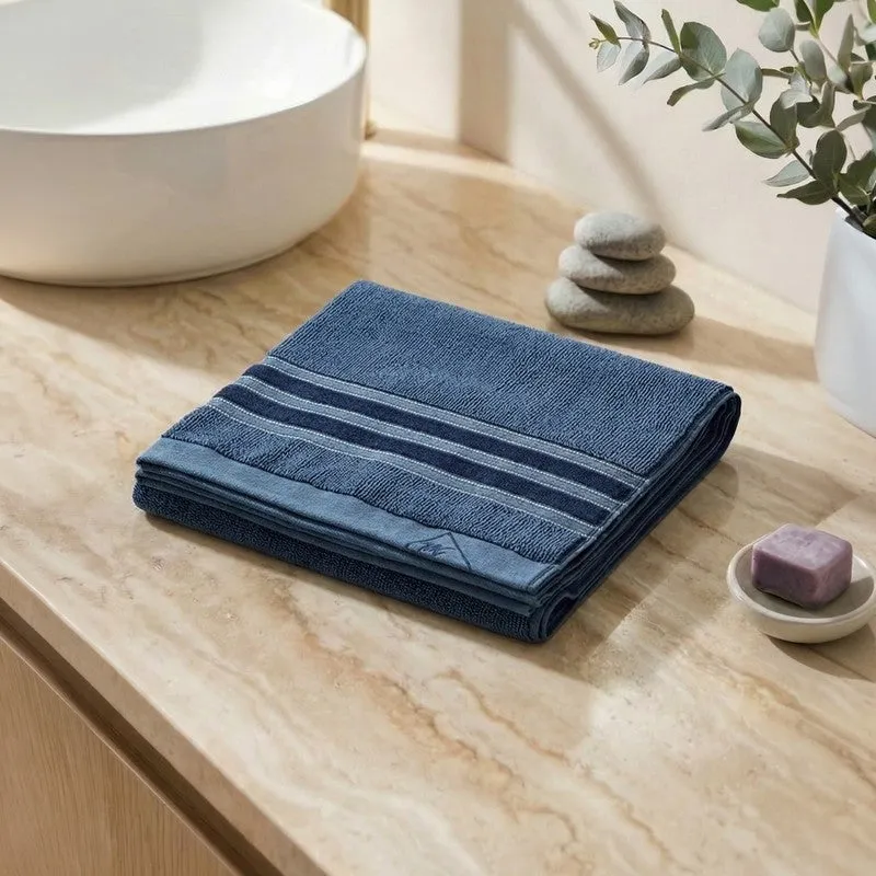 Folded blue bath towel with striped border on a bathroom counter