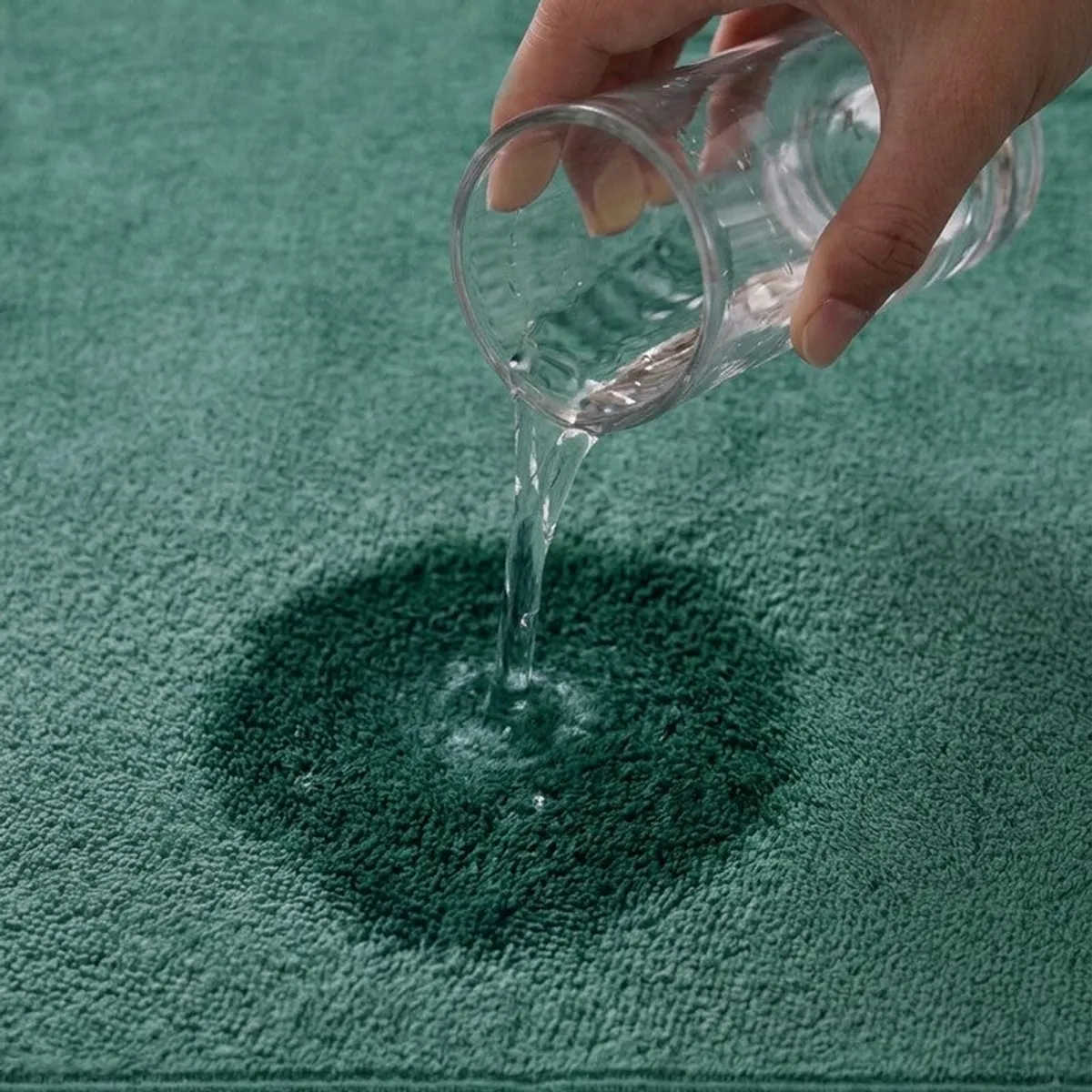Water being poured onto the textured surface of a green towel