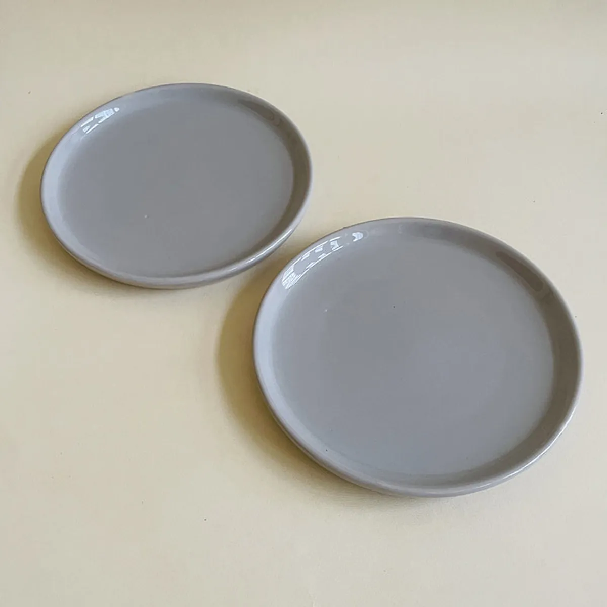 Two grey ceramic quarter plates shown at an angle with raised rims.