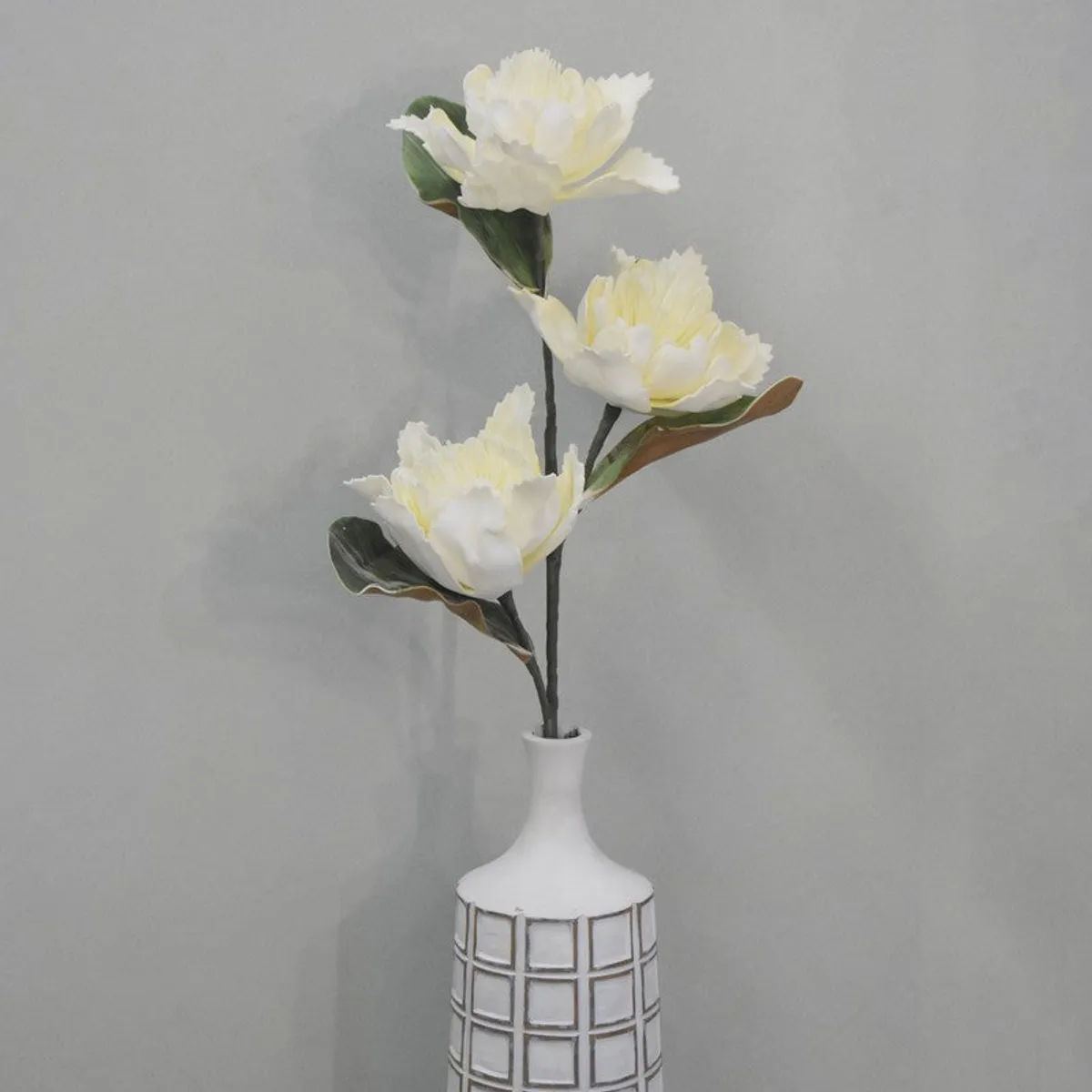 White artificial dahlia stem arranged in a tall decorative vase
