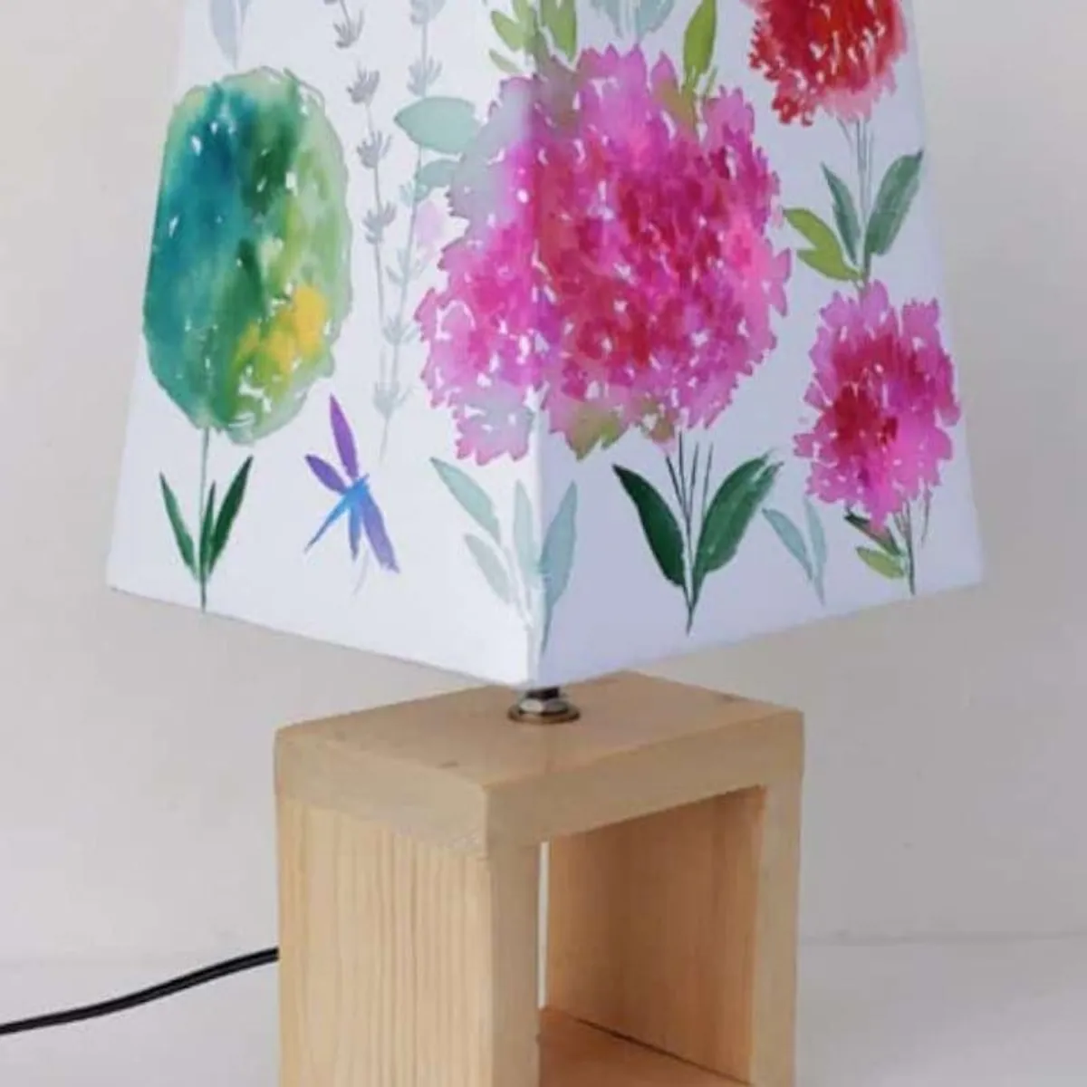 Floral fabric shade and light wood base shown with its electric cord