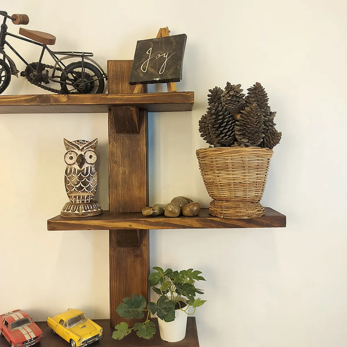 Close view of the rustic brown wooden shelf displaying an owl and potted plant.