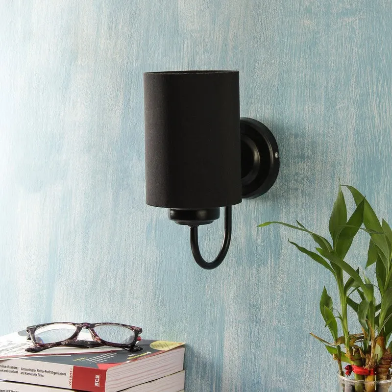Front view of black cotton shade wall lamp on a textured blue wall