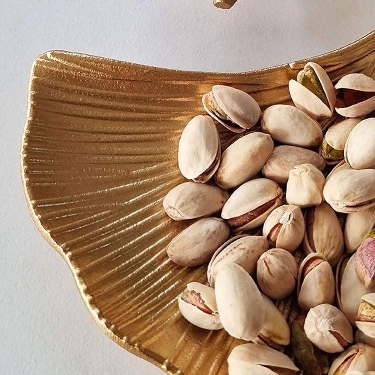 Close-up of the embossed ridged texture on a gold platter with pistachios