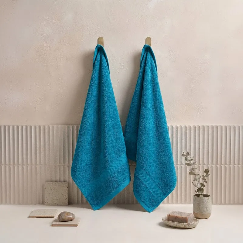Two blue hand towels hanging on wall hooks in a bathroom setting