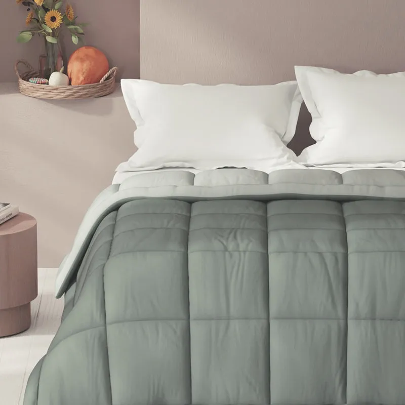 Grey quilted comforter styled across a bed in a neutral bedroom