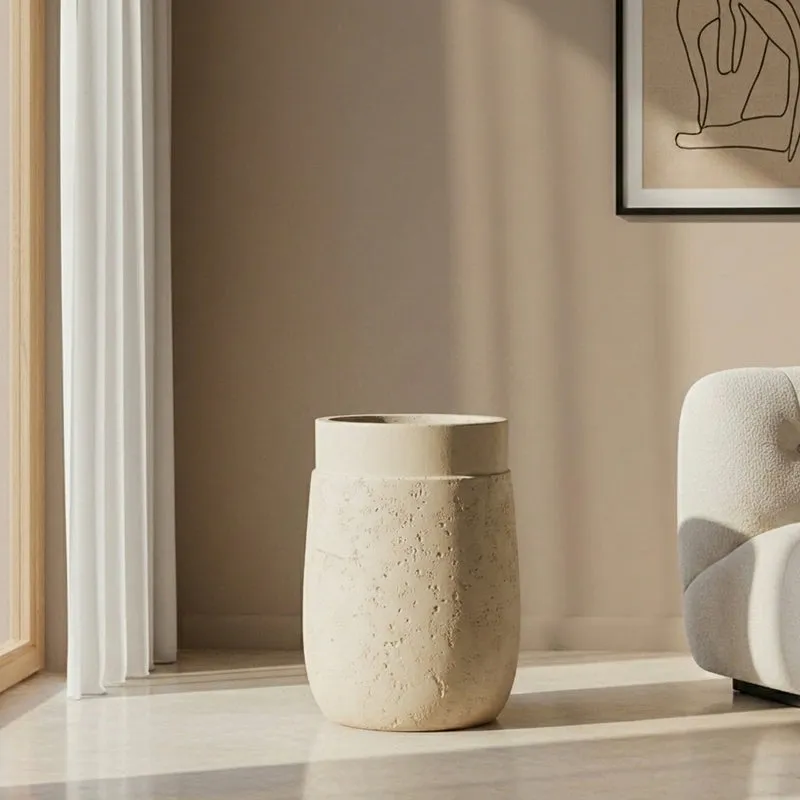 White cylindrical planter shown empty beside a sofa