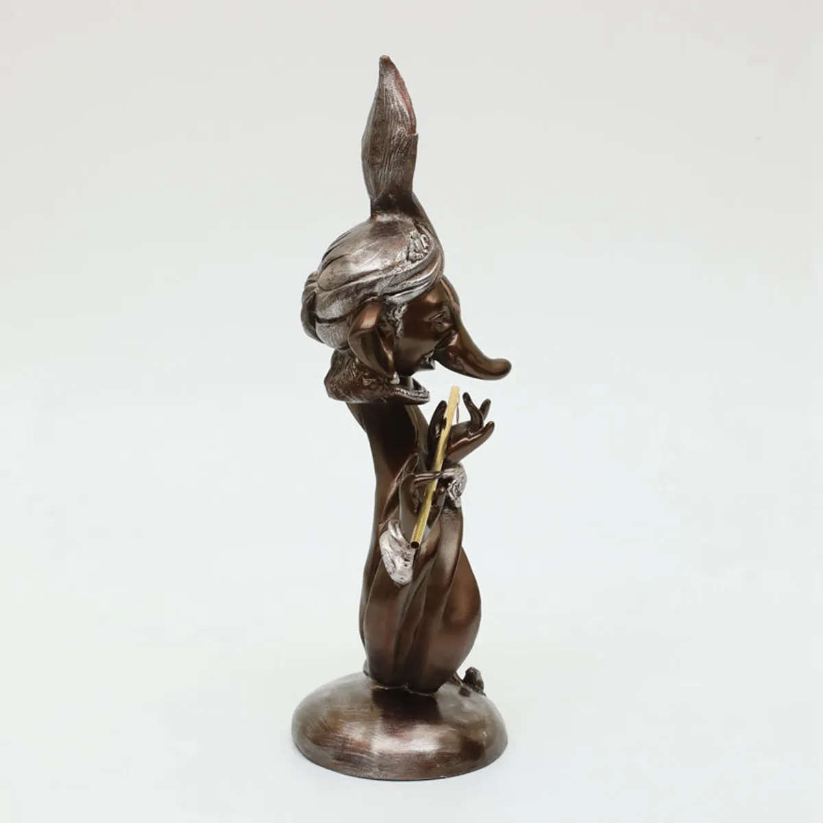 Side profile of a brown Ganesha showpiece with metallic accents on a white background