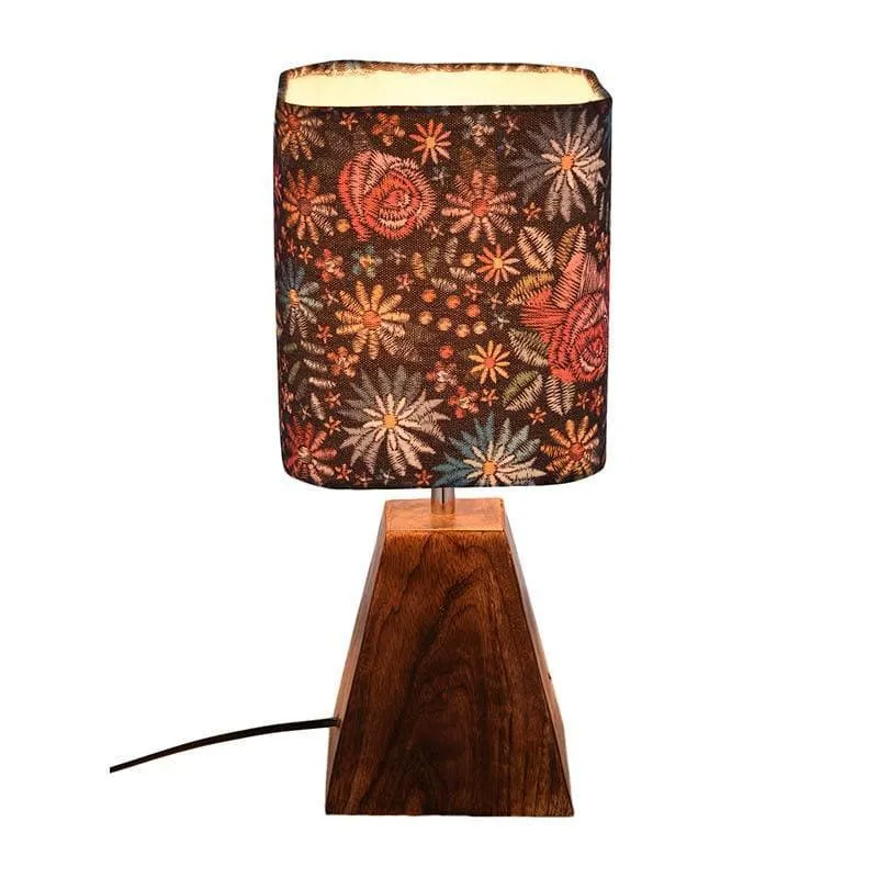 Lit multicolour floral table lamp with brown tapered base on white background