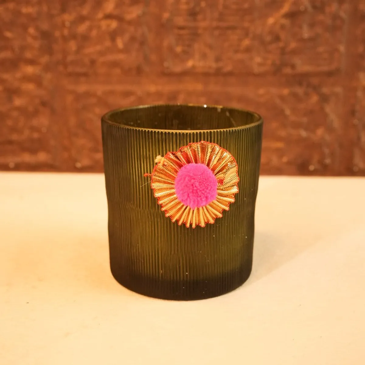 Close-up of the ribbed glass candle with a colourful decorative embellishment