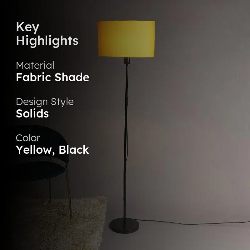 Yellow shade floor lamp with black stand against a dark background