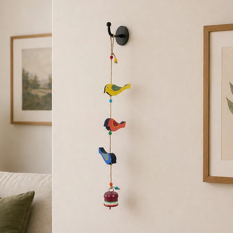 Multicolour bird windchime hanging from a wall hook in an interior setting