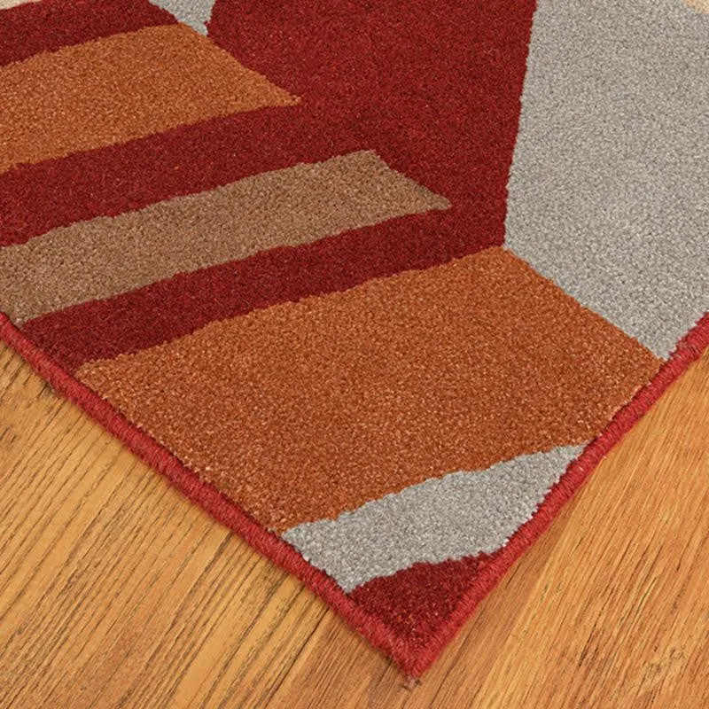 Close-up of carpet corner with geometric blocks in maroon, rust and grey