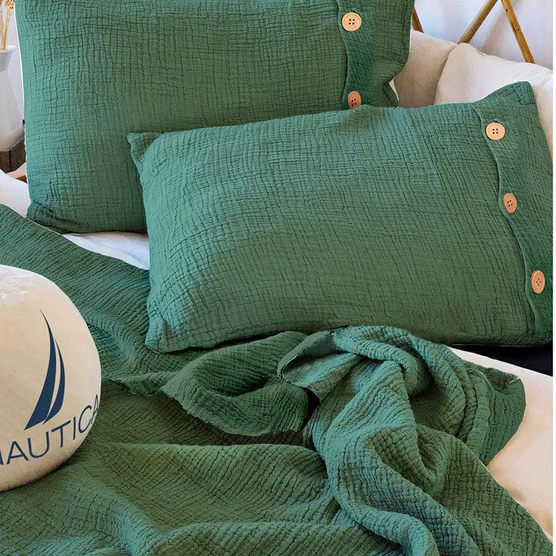 Close-up of green textured bedsheet and button-accented pillow covers