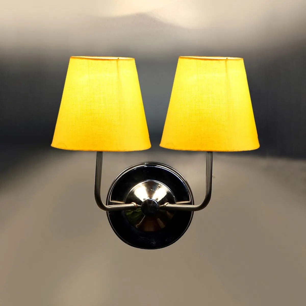 Front view of yellow shade wall lamp with round steel backplate