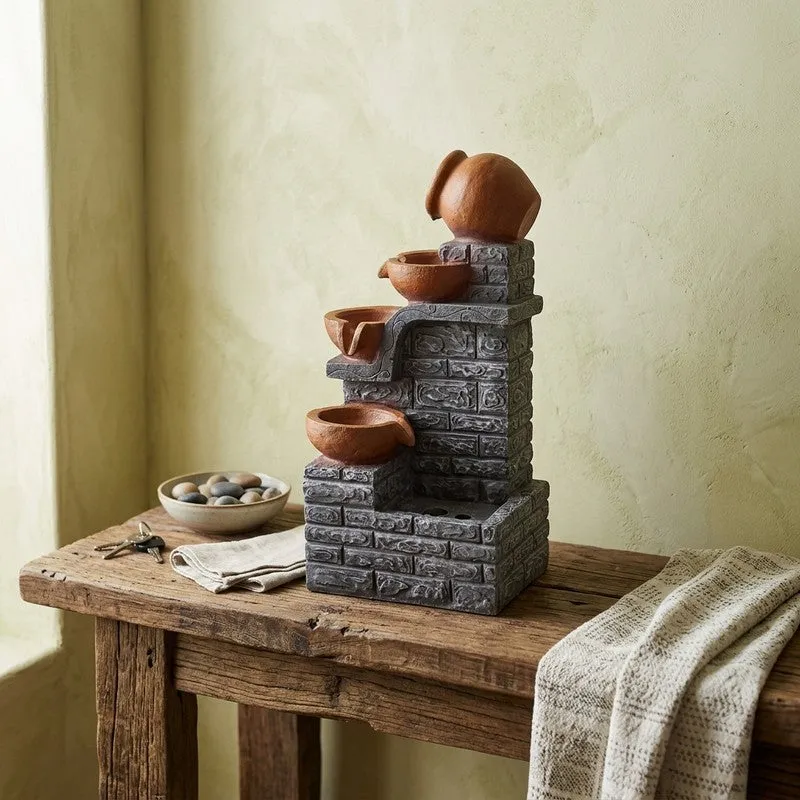 Layered brown bowl fountain with grey brick-textured structure on a rustic console
