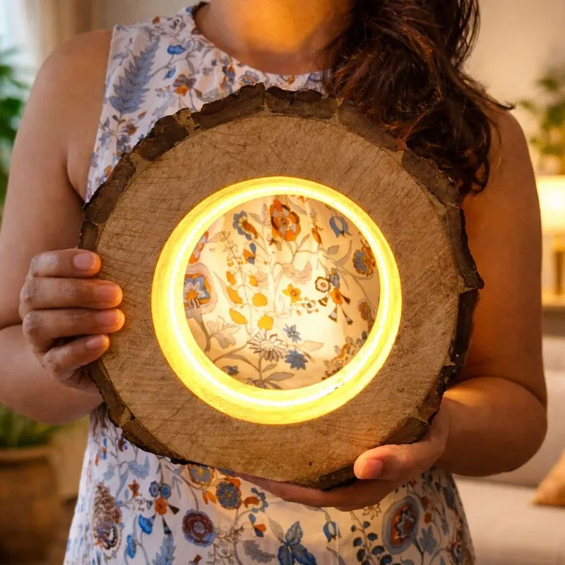 Person holding a round wooden table lamp with illuminated centre