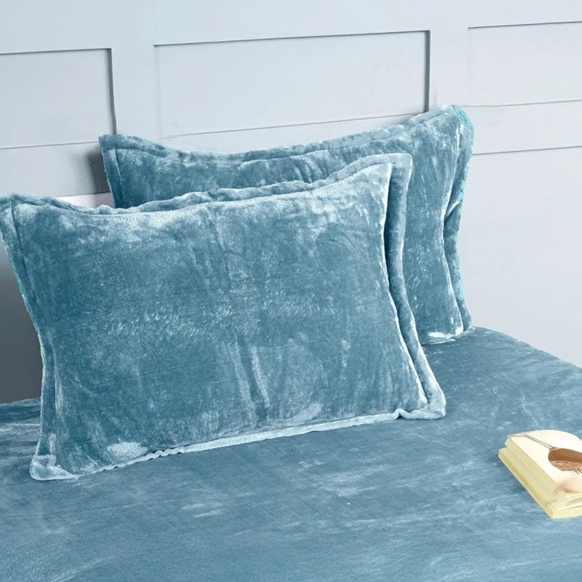 Two matching sky blue velvet pillow covers on the bedsheet