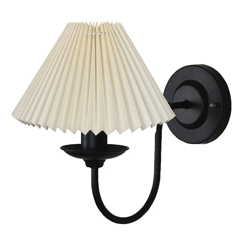 Ivory pleated wall lamp with black metal wall plate and curved arm on a white background