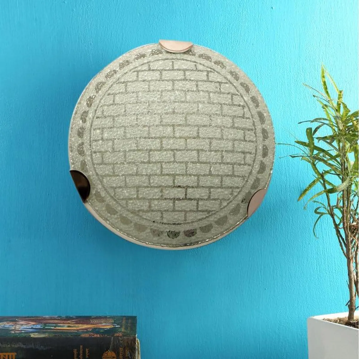 Unlit round grey wall lamp with textured surface on a blue wall