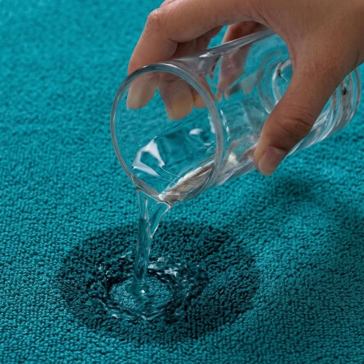 Water being poured onto a blue towel surface in close-up