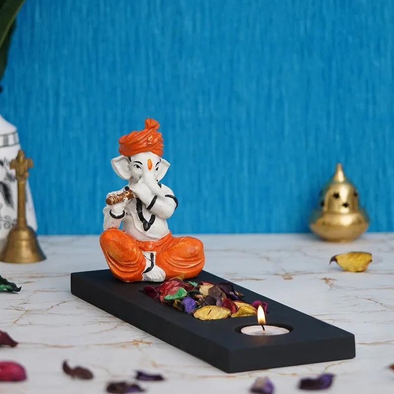 Ganesha tea light holder on a black rectangular base with a lit candle