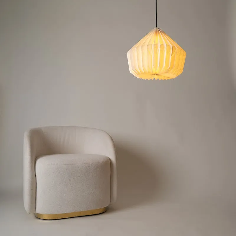 Off-white pendant lamp hanging above a rounded upholstered chair