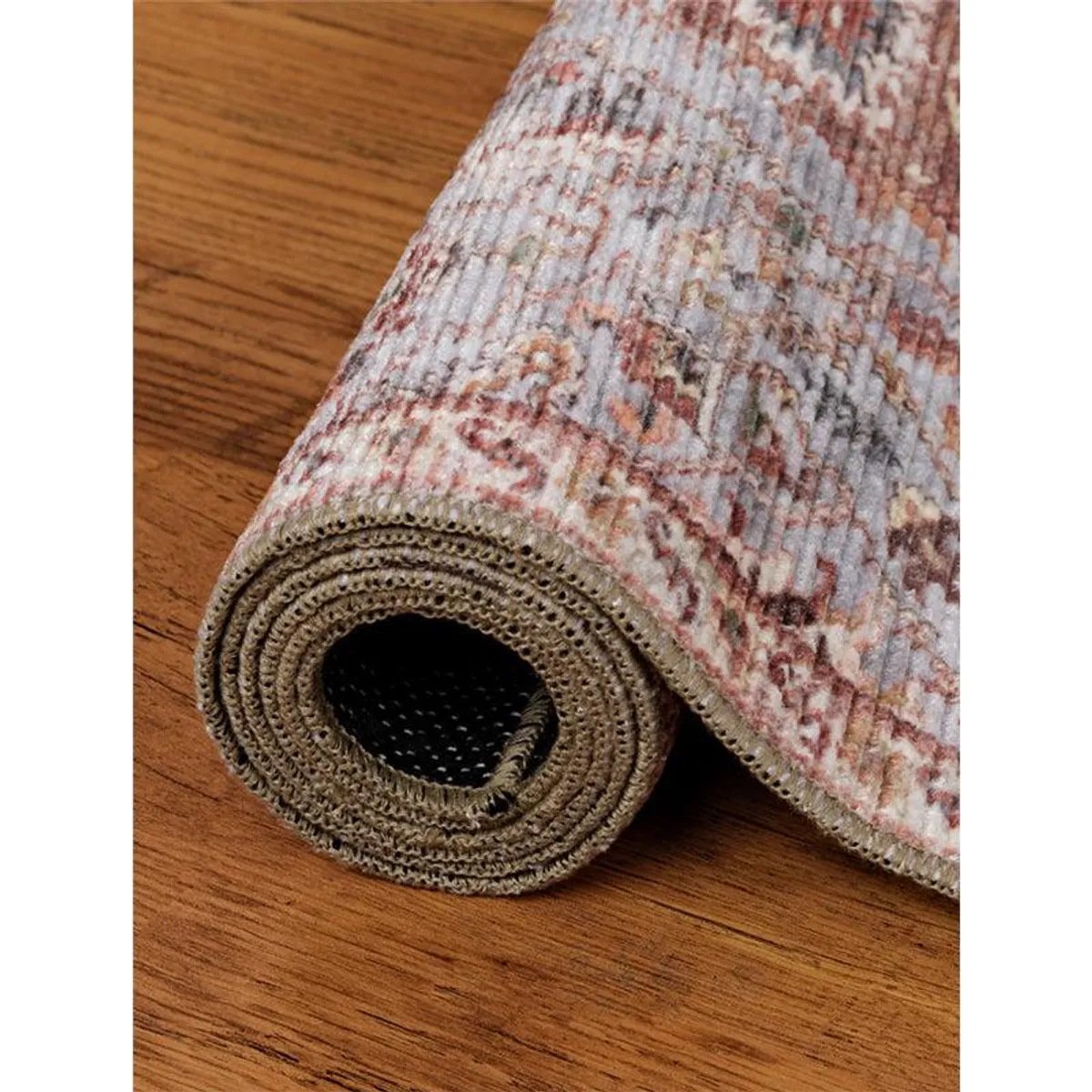 Rolled carpet showing its patterned surface and edge on a wooden floor