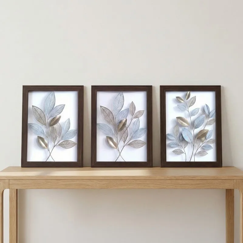 Set of three framed botanical artworks displayed on a light wooden console table