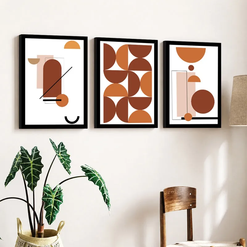 Three framed geometric wall art prints styled on a cream wall with indoor plants
