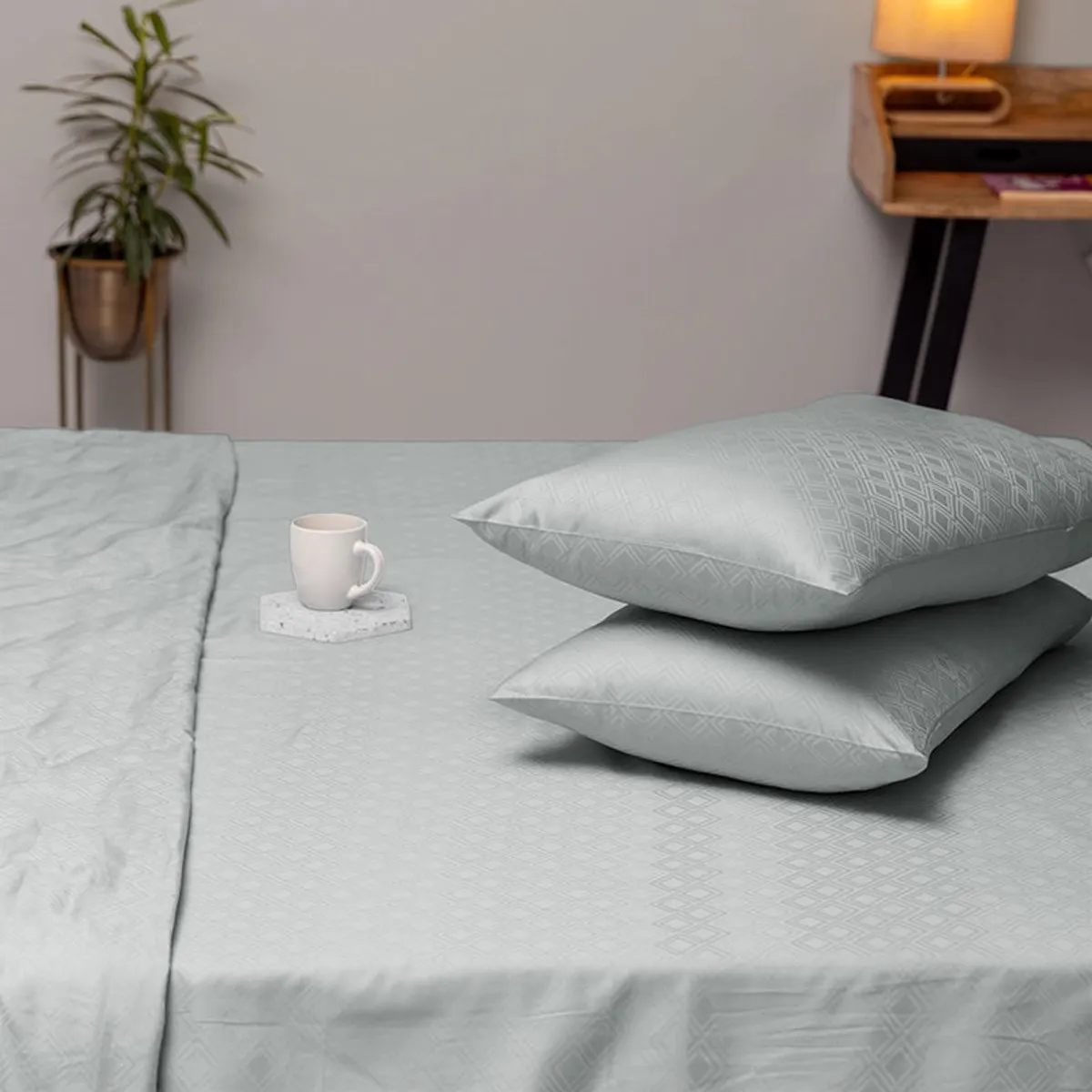 Light grey geometric duvet cover spread across a bed with pillows