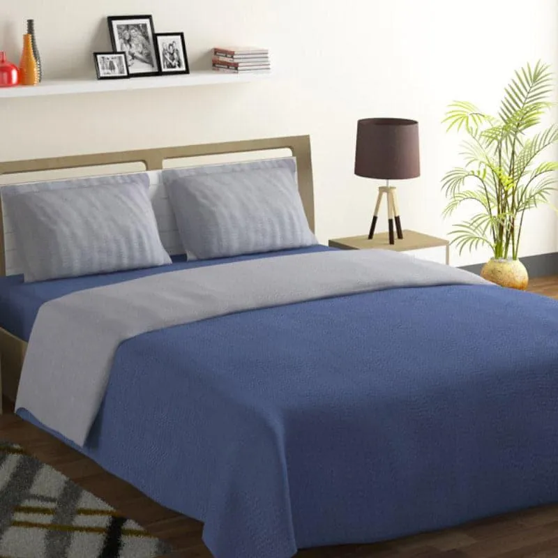 Styled bed with navy blue bedsheet and grey top sheet