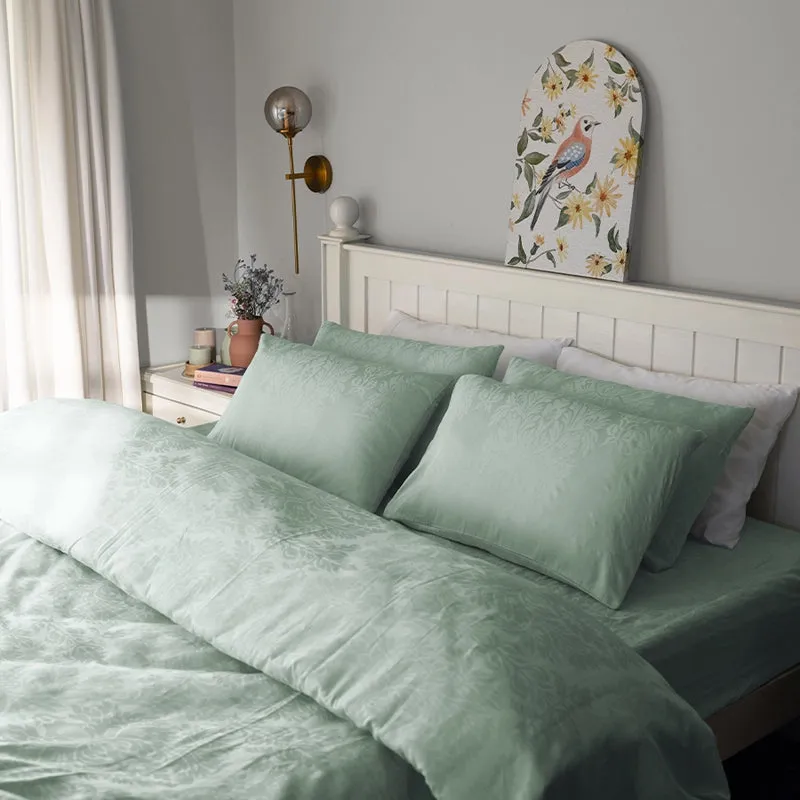 Sage green floral bedding set styled on a white bed