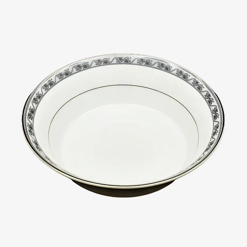Close-up of a white oval porcelain bowl with an ornate floral border.