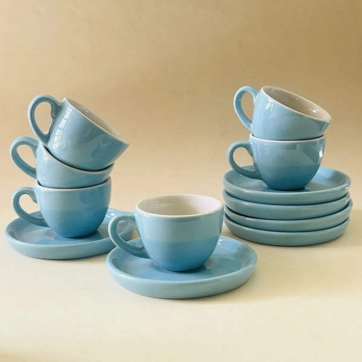 Blue ceramic cups and saucers stacked against a warm neutral background
