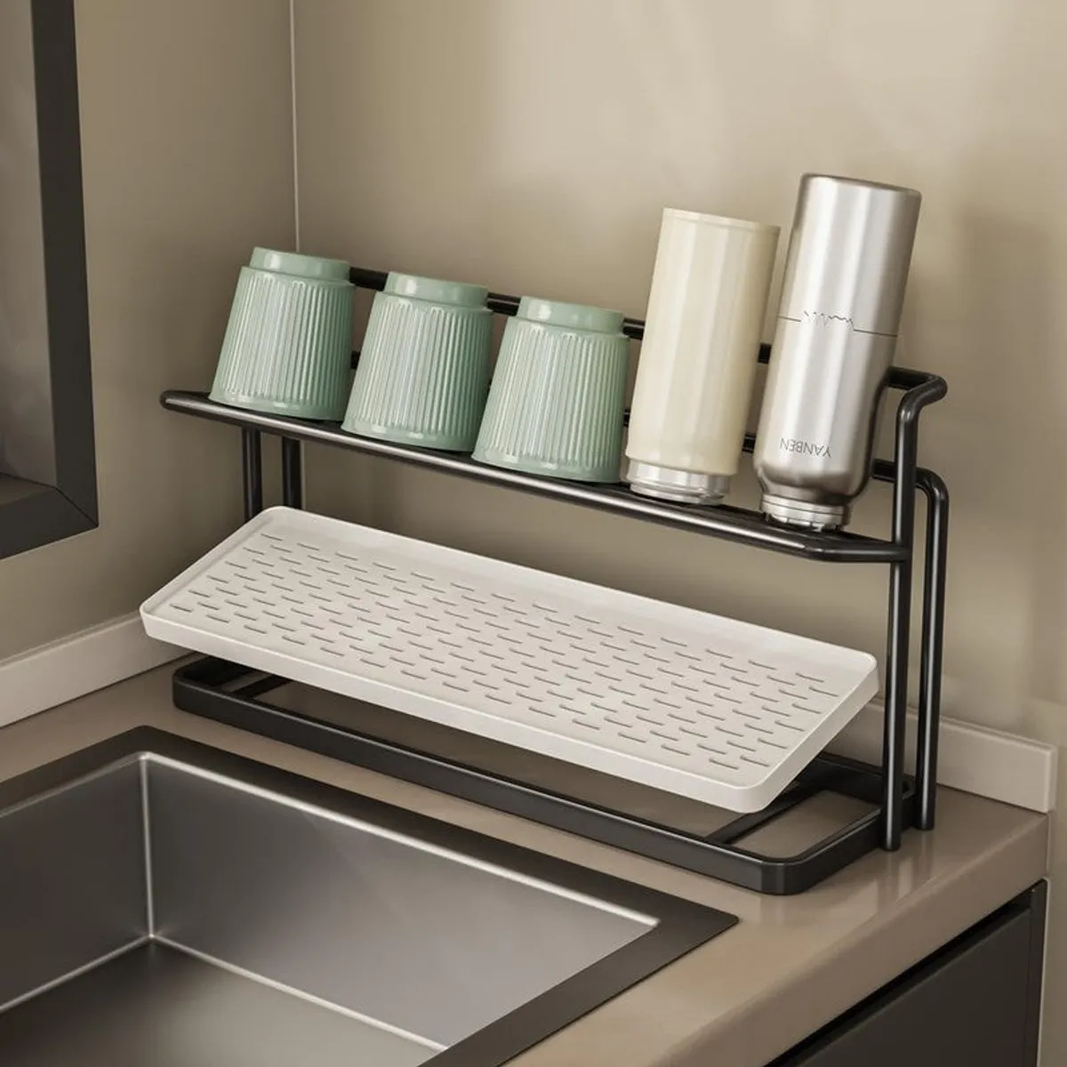 Black two-tier rack with removable white tray displayed near a sink