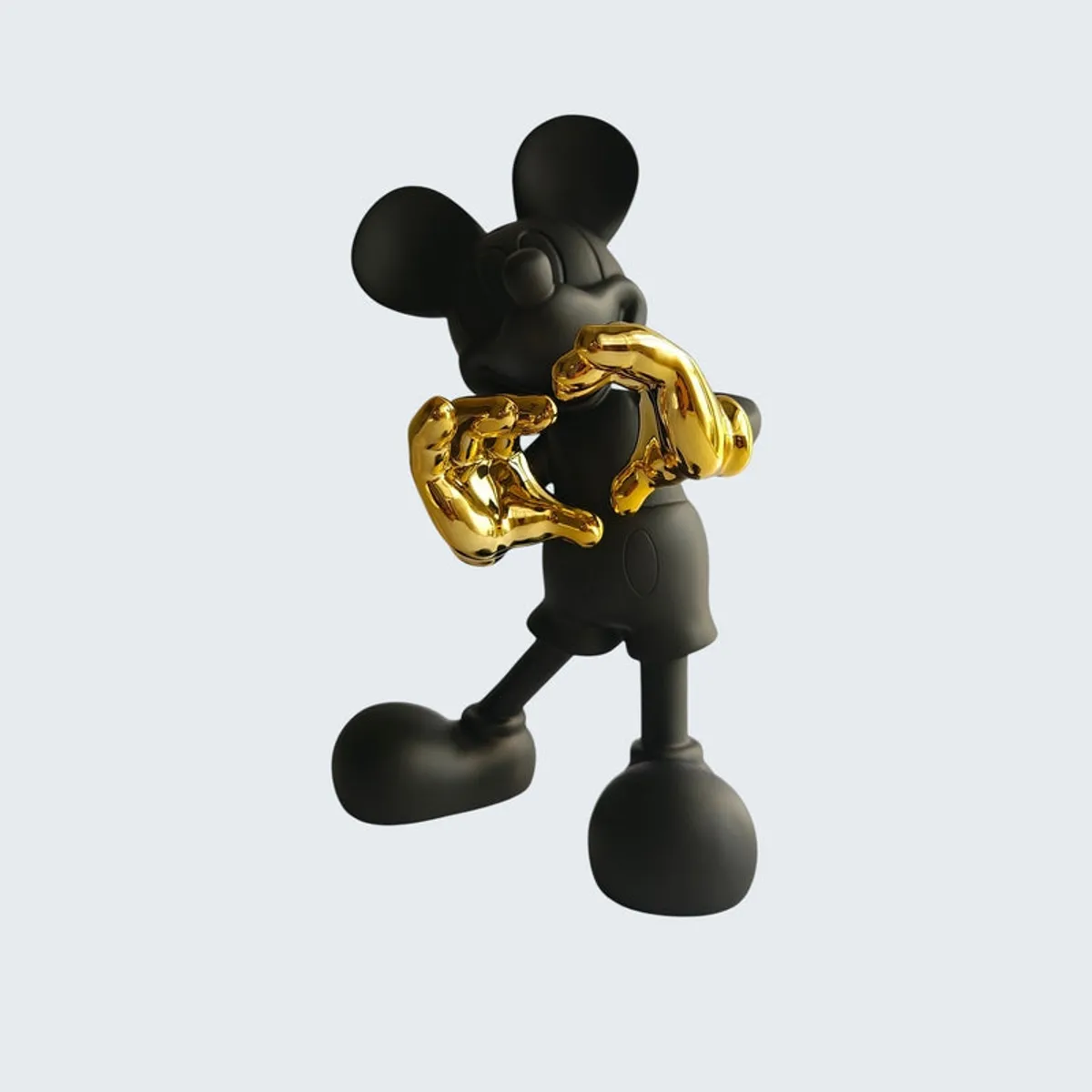 Back angled view of the black figurine with gold gloves on a pale background.