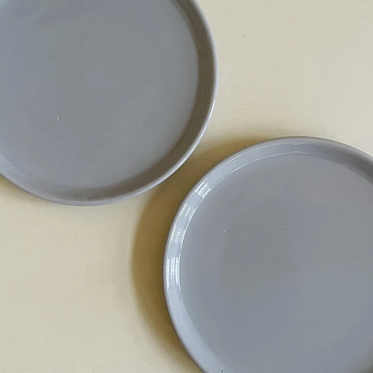 Close-up of two glossy grey ceramic plates with smooth raised edges.