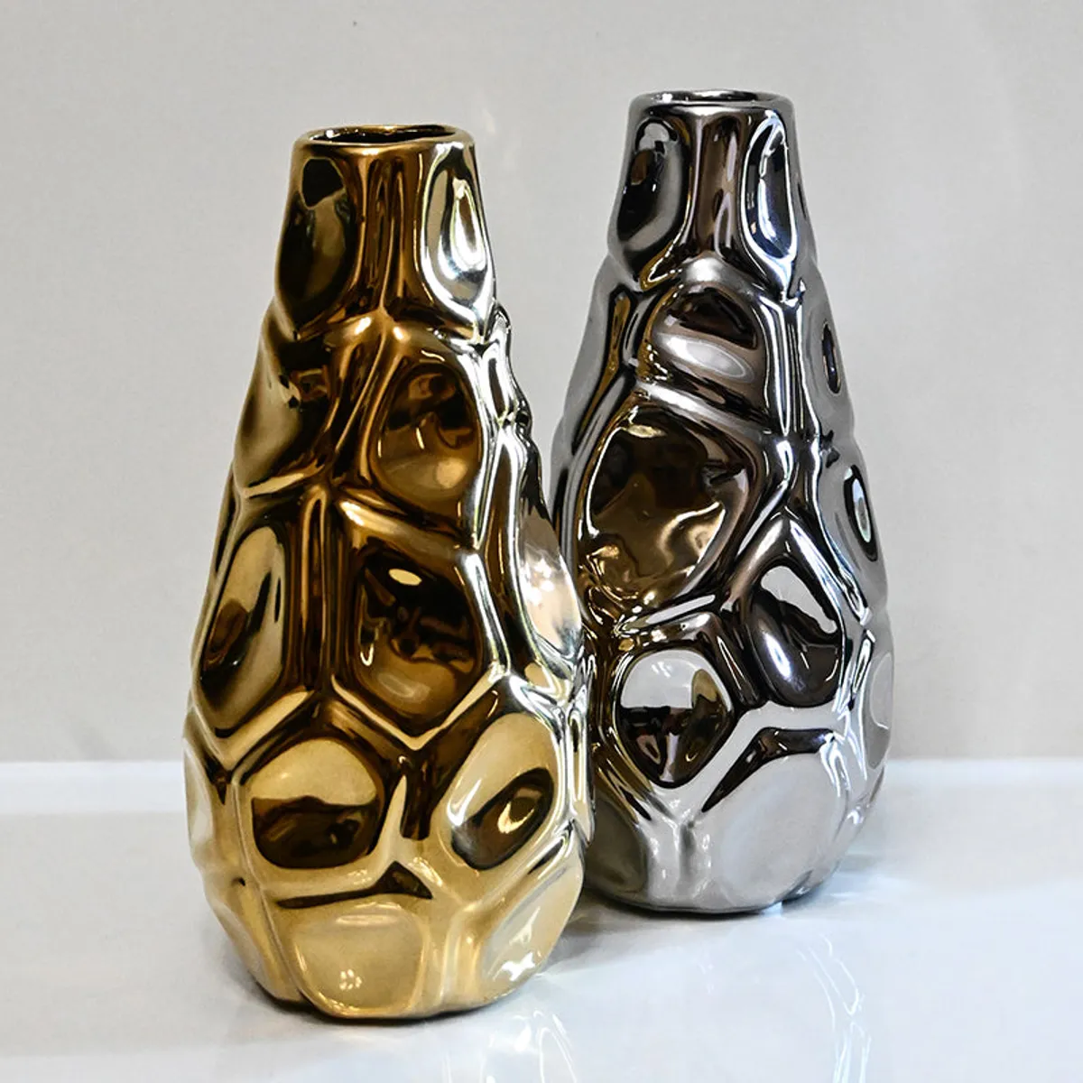 Gold and silver ceramic vases with reflective finish on a white surface